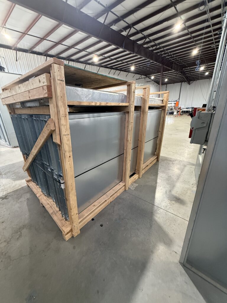 Large metal industrial equipment secured in a wooden crate inside a warehouse.